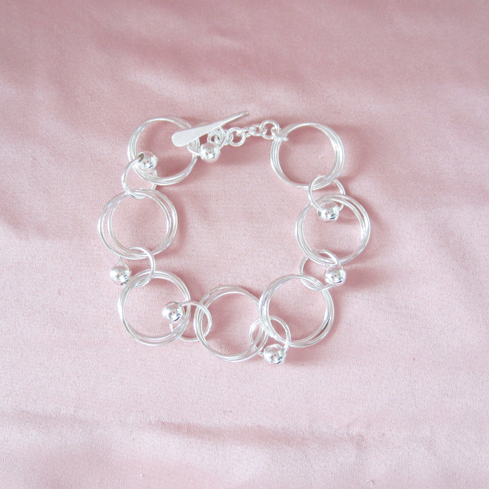Pulsera plateado argollas dobles bolitas